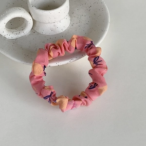 Détail d'un chouchou rose en tissu à motifs floraux sur un plateau en céramique blanche