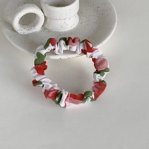 Gros plan d'un chouchou en tissu blanc à motif de fraises sur un plateau en céramique
