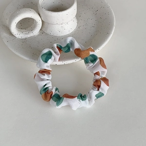 Détail d'un chouchou blanc à pois verts sur un plateau en céramique épuré