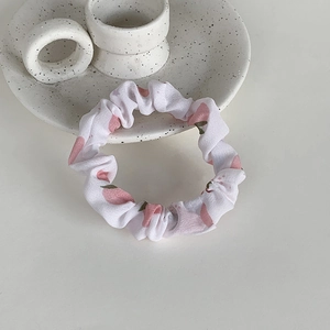 Détail d'un chouchou en tissu blanc avec de mignons motifs de pêches roses