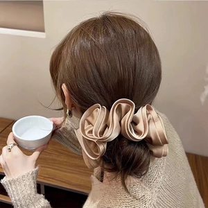 Detailed view of oversized champagne satin hair scrunchie styled on a low bun hairstyle