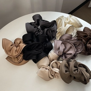Detail showing various silk satin scrunchies in neutral colors with elegant textures