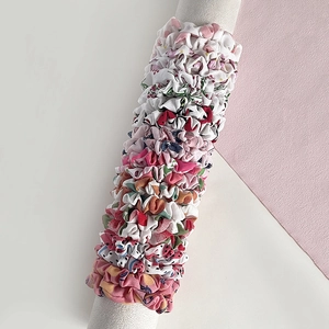 Détail de chouchous en tissu avec motifs floraux et fruités sur cylindre blanc