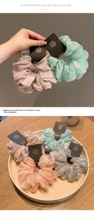 Nahaufnahme von plissierten Organza-Haargummis in Pastellfarben mit goldfarbenen Anhängern
