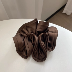 Detail of dark brown pleated silk hair scrunchie with elegant satin sheen and rich texture