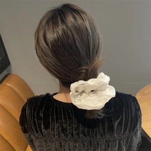 Chouchou en satin blanc avec broderie de cœur sur cheveux foncés en décor réel
