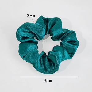 Close-up of dark green satin scrunchie showing 9cm diameter and 3cm width measurements