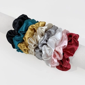 Set of eight assorted satin scrunchies in metallic colors displayed on a white stand