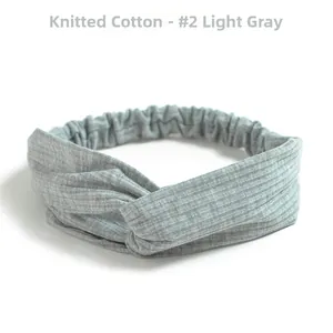 Detail of light grey knitted cotton headband showing ribbed texture and knotted cross design