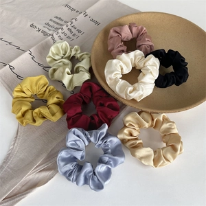 Detailed set of eight assorted silk satin scrunchies displayed on a ceramic dish and linen