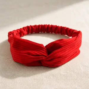 Detail of red knitted cotton headband with ribbed texture and twisted knot design