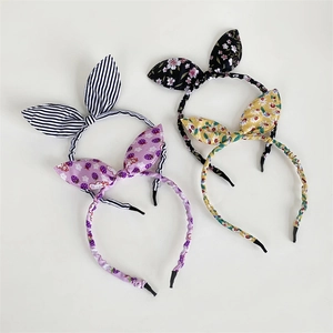 Close-up of four fabric bow headbands with floral, strawberry, and striped patterns