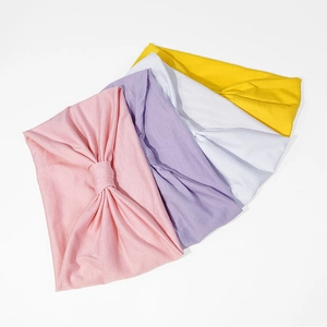 Dettaglio di quattro fasce per capelli in cotone annodate nei colori rosa, viola, bianco e giallo