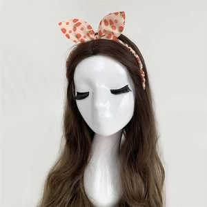 Detail of sweet strawberry print bow headband on a long brown hair mannequin head