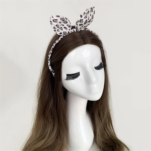 Detail of leopard print bow headband on brown hair model showing the fabric texture