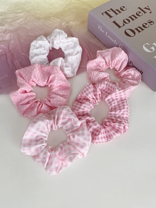 Detailaufnahme von fünf Haargummis mit rosa Punkten und Karomuster aus Stoff