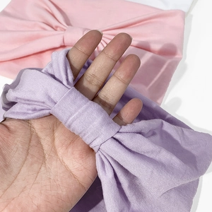 Dettaglio di due fasce elastiche per neonati con grandi fiocchi in rosa e viola