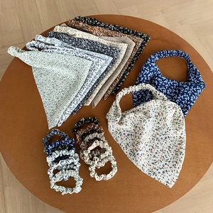 Gedetailleerde set gebloemde driehoekige hoofddoeken en bijpassende scrunchies op houten tafel