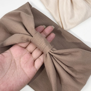 Dettaglio della trama in maglia elastica e del design a nodo delle fasce larghe per capelli