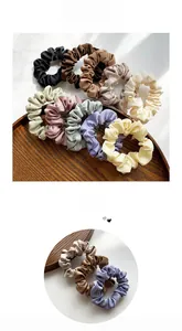 Detailed view of assorted satin silk scrunchies in multiple colors on a wooden tray