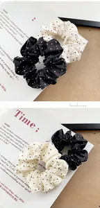 Close-up of black and cream polka dot satin scrunchies with elegant pleat textures