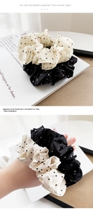 Detail view of black and white polka dot satin hair scrunchies set on magazine background