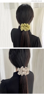 Detail of glossy satin oversized scrunchies in olive green and beige on dark hair