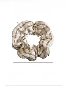 Dettaglio di scrunchie in tessuto gingham marrone con diametro 12 cm e larghezza 4 cm
