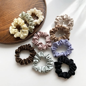 Elegant set of nine silk satin scrunchies in minimalist solid Morandi colors on a tray