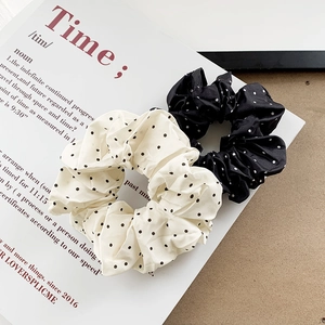 Elegant set of black and white polka dot satin scrunchies displayed on a magazine