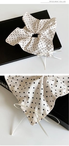 Détail d'un chouchou crème à pois avec bordure en dentelle et nœud en ruban blanc