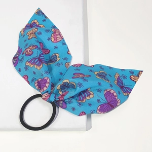 Detailed close-up of a blue butterfly pattern bow hair tie with high-elastic black rubber band