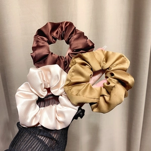Three-piece set of elegant satin hair scrunchies in brown, gold, and beige tones