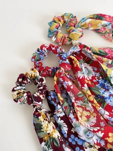 Close-up of three floral print scrunchies with long ribbons in vibrant chiffon fabric