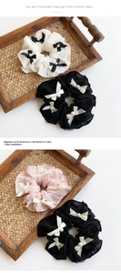 Detailed close-up of lace scrunchies with satin bows and pearls on a wooden tray
