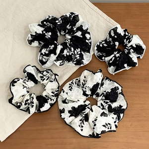 Elegant 4-piece set of black and white ink floral print hair scrunchies on wooden background