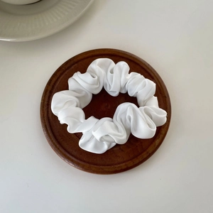 Elegant beige satin scrunchie with creamy texture on a dark wooden tray accessory