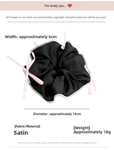 Detail view of a 14cm satin scrunchie with pink ribbon bow showing size and fabric texture