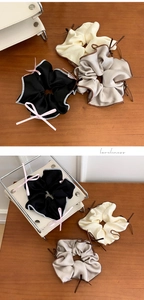 Detail view of satin silk scrunchies with elegant ribbon bows in multiple soft colors