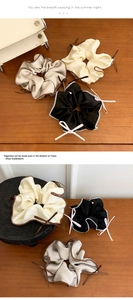 Detail of satin scrunchies with ribbon bows and contrast piping on a wooden surface