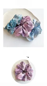 Detailed view of tie-dye satin scrunchie with blue and purple gradient silk texture