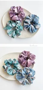 Detailed view of three-piece tie-dye satin scrunchies in purple, teal, and blue