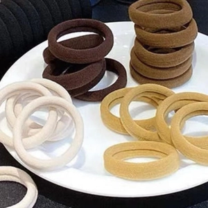 Detail view of seamless elastic hair ties in neutral earth tones on a white tray display