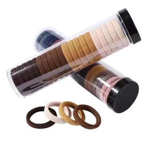 Macro view of high-elastic seamless hair ties in assorted earth-tone colors in a clear jar