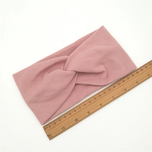 Detail showing pink ribbed knit headband with twist knot design measuring 20cm long