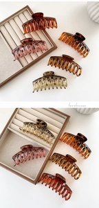 Detail view of large resin hair claws with tortoise shell patterns on a wooden tray