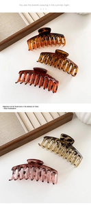 Detail showing various colors of large acetate claw clips on a warm wooden display