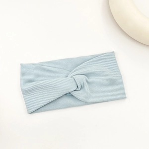 Detail of light blue ribbed knit headband with elegant twisted knot design on white surface