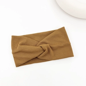 Detail of caramel ribbed knit headband with elegant cross knot design on white background
