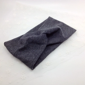 Detail of dark grey ribbed knit headband featuring a central twist design on lace background
